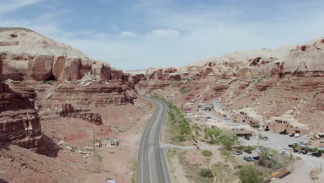 Luftaufnahme-Einer-Isolierten-Asphaltstraße-Entlang-Hoch-Aufragender-Klippen-Aus-Rotem-Sandstein-In-Bluff,-Utah,-USA