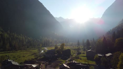 val di mello in sondrio, italy, old houses and vegetation, mountains and between them the sun shining. aerial cinematic shot .
