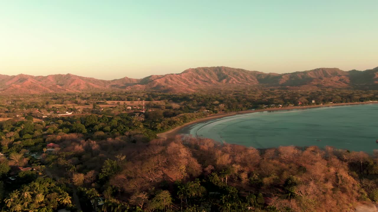 disparo de drones en órbita aérea de olas verdes rompiendo en la playa de flamingo al atardecer