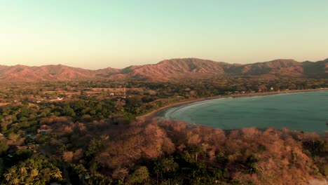 aerial orbit drone shot of green waves breaking on flamingo beach in sunset