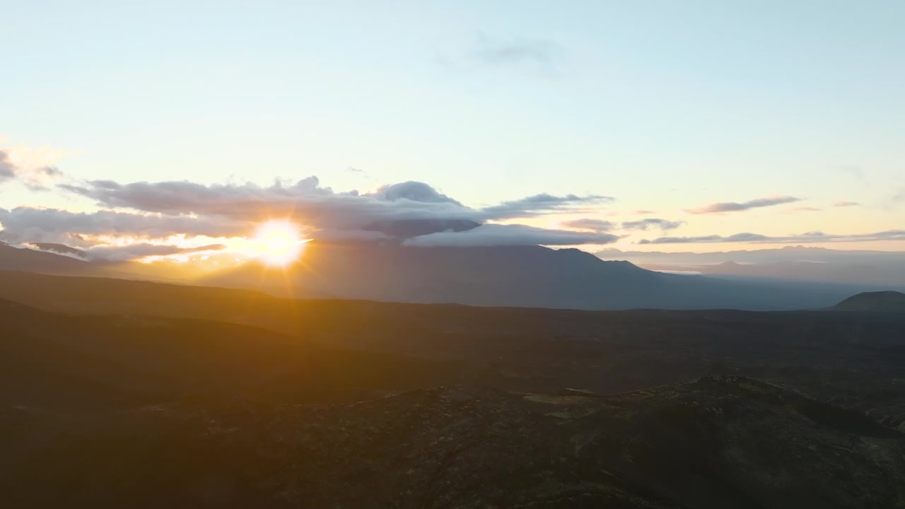 Imágenes aéreas de la dramática luz del atardecer sobre la meseta volcánica de Tolbachinsky Dol con nubes y siluetas de montañas distantes, Krai de Kamchatka, Rusia.