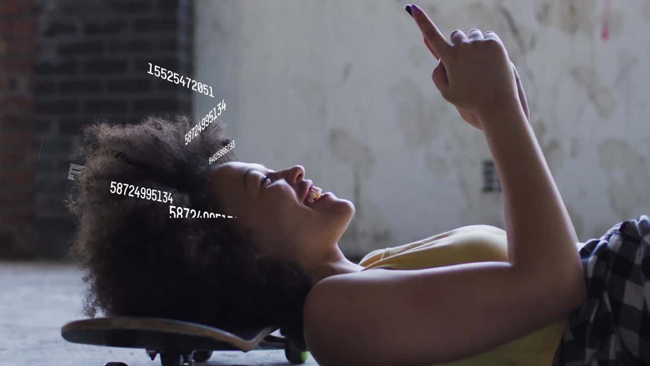 woman lying on skateboard in warehouse, pointing at floating data charts for tech presentation