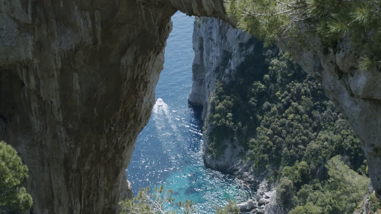 vista de un barco de vela a través del arco natural en capri en cámara lenta