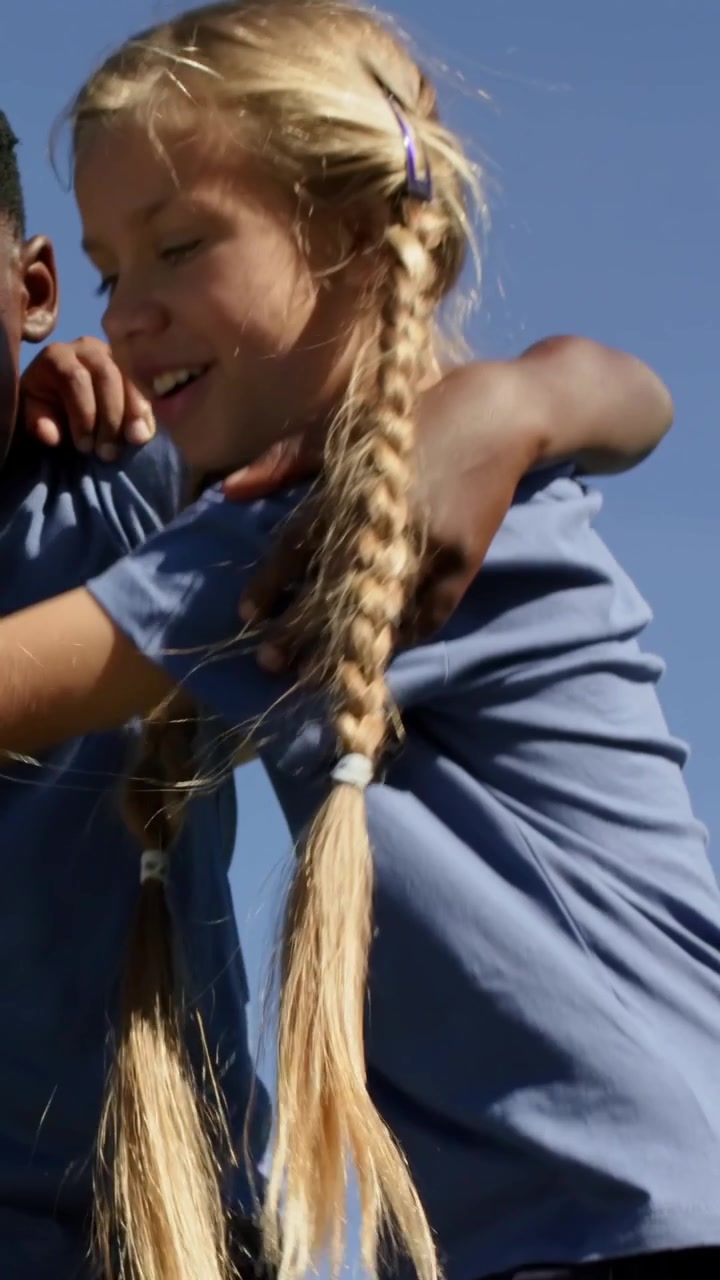 Vertical video: Linking arms three kids leaning as braid swinging, looking at school blue shirts