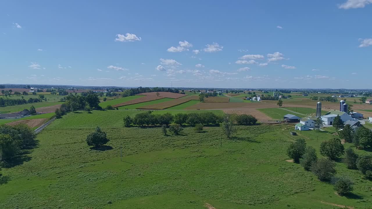 una vista aérea de granjas, silos y tierras de cultivo que pronto serán cosechadas con un caballo amish y un buggy viajando a través de él