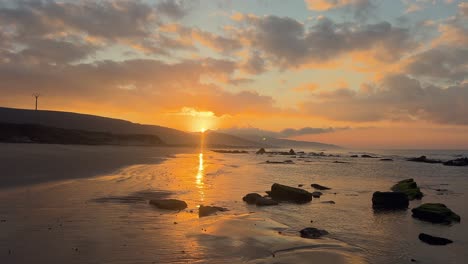 a peaceful, rocky beach at low tide with a magnificent sunset in the distance