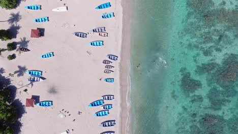 Vista-Aérea-De-Arriba-Hacia-Abajo-De-Una-Exótica-Playa-De-Arena-Con-Pequeñas-Embarcaciones-Y-Nadadores-Varados