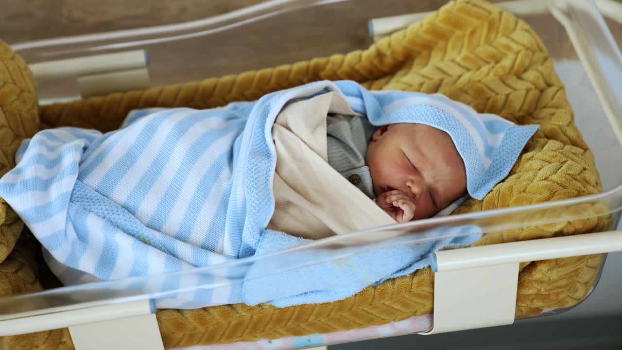 Neonato che dorme in una culla ospedaliera