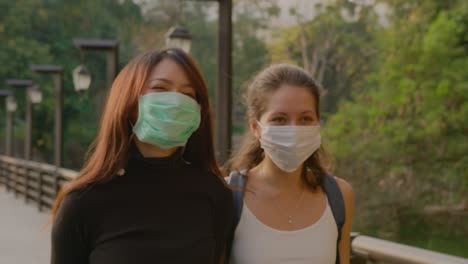 two women wearing masks walking in a park