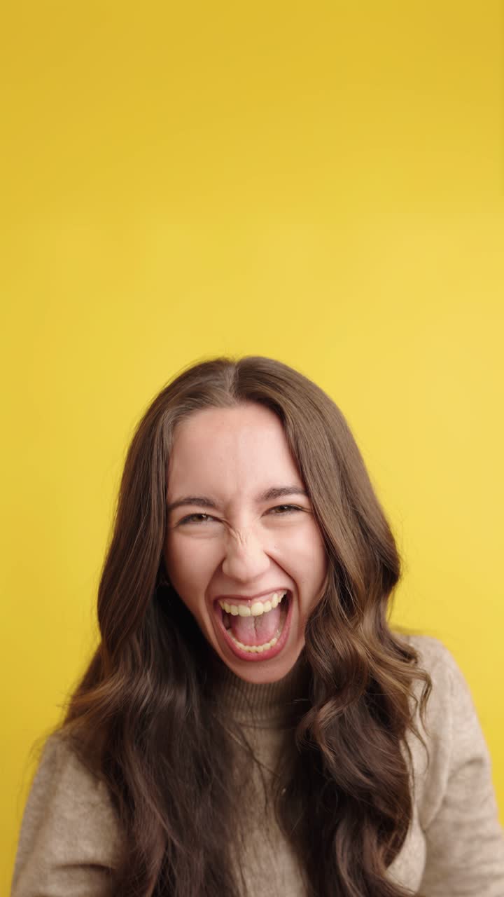 Expressive woman laughing and screaming with joy on yellow background