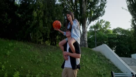 young couple having fun playing basketball in the park