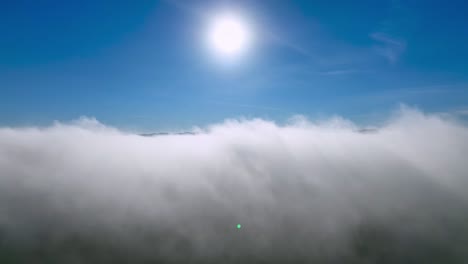 AERIAL-PUSH-THROUGH-CLOUDS-TOWARD-THE-SUN-TO-REVEAL-THE-BRUSHY-MOUNTAINS-NEAR-WILKESBORO-NC,-NORTH-CAROLINA