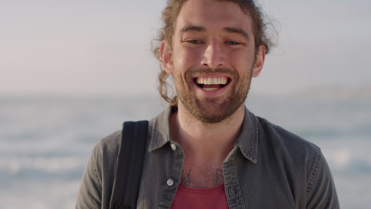 ritratto di un giovane uomo caucasico che ride godendosi le vacanze, i viaggi, la soddisfazione dello stile di vita su una spiaggia calda e soleggiata in slow motion