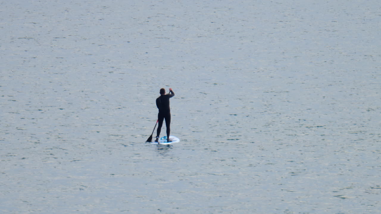 Distant view of a man standup paddle boarding on the sea