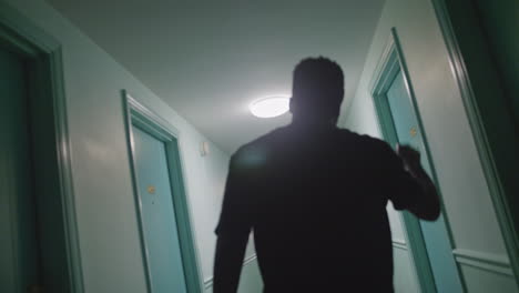 African American male stumbling into a wall in a hallway