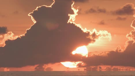 puesta de sol naranja con nubes tocando el agua del océano