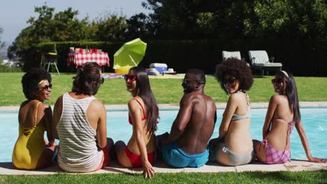diverse group of friends sitting in a row looking at the camera at a pool party