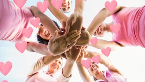 animation of hearts over happy diverse women teaming up