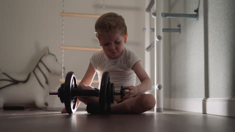 Concentrated-little-boy-prepares-heavy-bar-for-training
