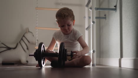 concentrated little boy prepares heavy bar for training