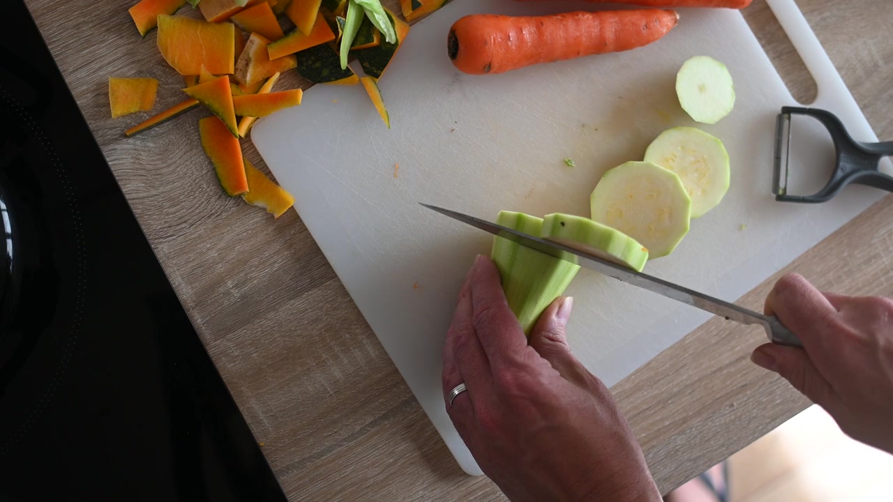 Persona che affetta zucchine fresche su un tagliere