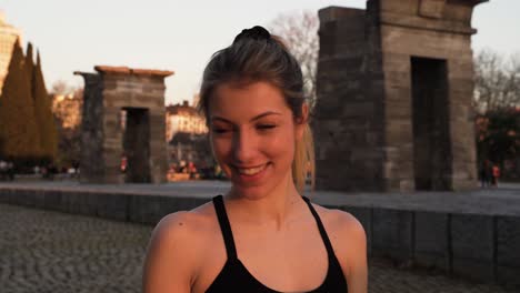 confident young blond fitness woman smiling at camera in city park