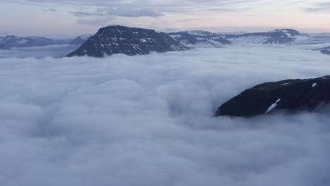 magnificent view of fjord covered in low clouds and large mountain peaks, aerial