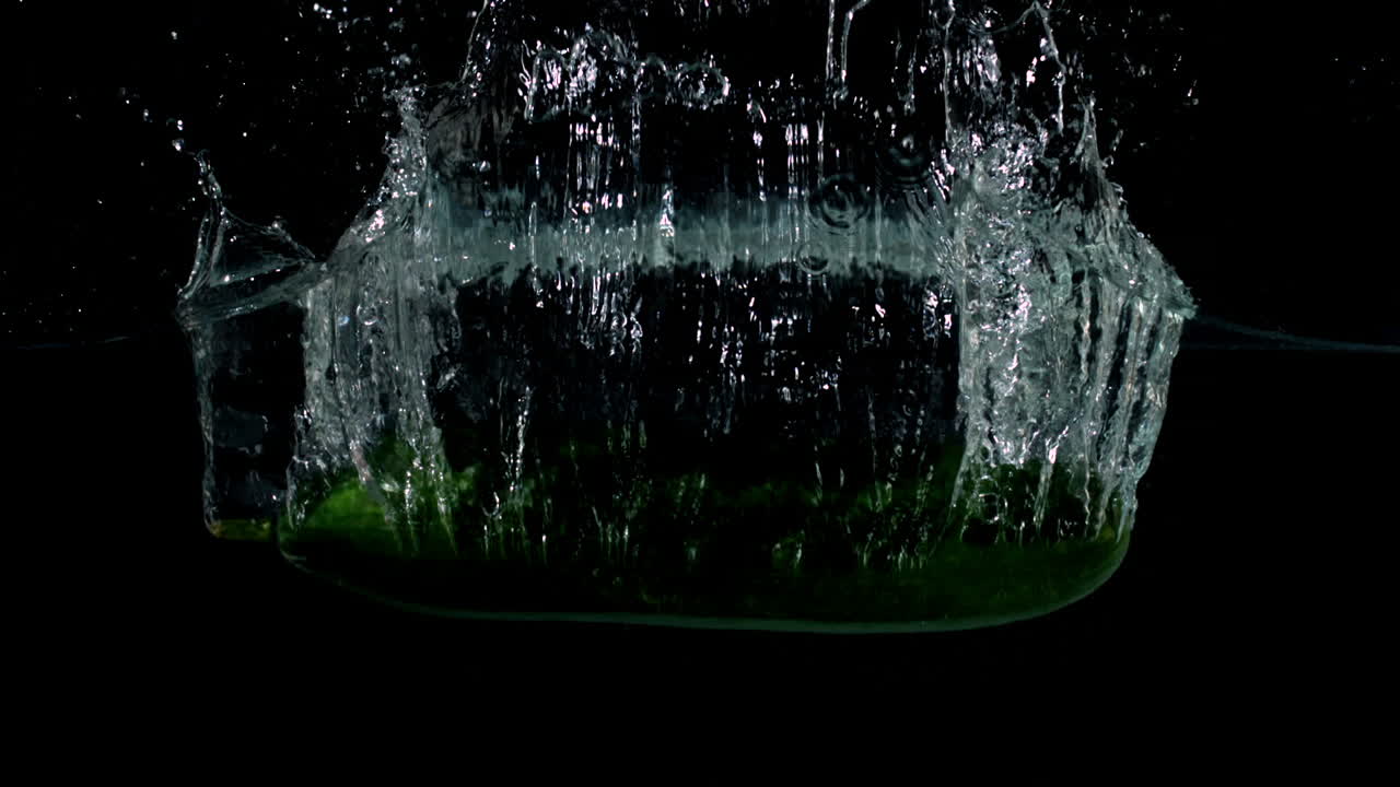 Courgette falling in water on black background