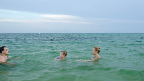 boy in sea walking from mother to father