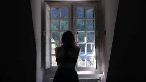 young attractive caucasian woman opening a window in a cottage home in france