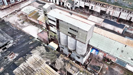 ruined old factory buildings. damaged walls, roofs and scattered debris. aerial view. new modern building at the backdrop.