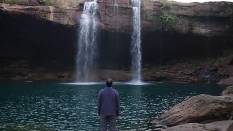 Junger-Mann,-Der-Den-Natürlichen-Wasserfall-Genießt,-Der-Morgens-Vom-Berggipfel-Fällt