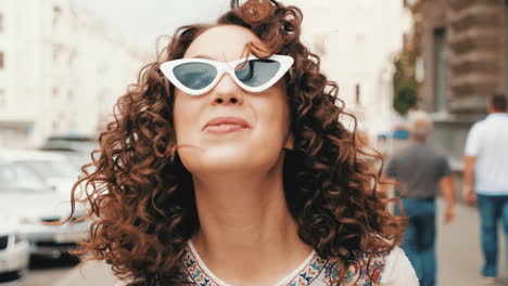 smiling woman in white sunglasses with curly hair on the street