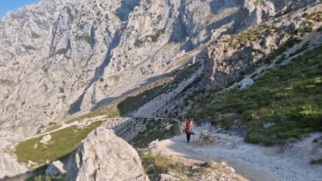 brunette girl with walking sticks and backpack hiking on the cares route, asturias