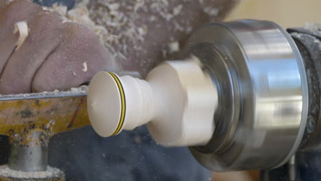 slow motion shot of male carpenter using chisel for shaping piece of wood on lathe