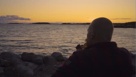 grown male viking sitting by the waters sea ocean smoking antique ancient pipe releasing streams of smoke looking ahead towards better days calming environment peaceful atmosphere with sense of being