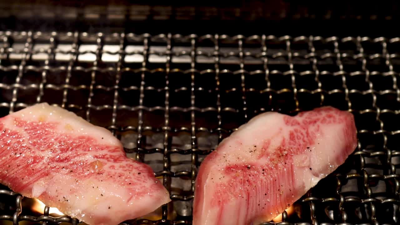 Slices of marbled beef sizzling on a metal grill, showcasing the cooking process.