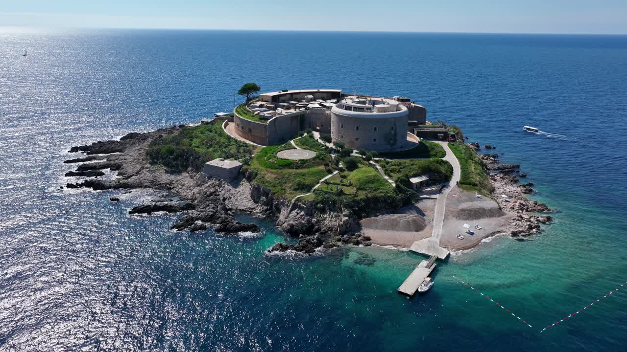 Drone flyover orbit establishing of Mamula Island with surrounding turquoise water and historic structure visible