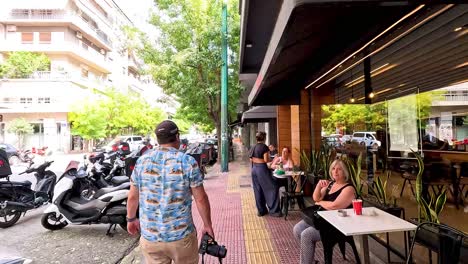 people walking past cafes and parked scooters