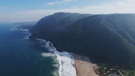 aerial view of playa grande in quintay, showcasing its stunning green cliffs and expansive coastline under a clear sky, capturing the beauty and tranquility of the ocean landscape.