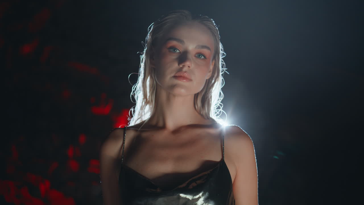 Sensual blonde posing dark background closeup. Fabulous model in party light