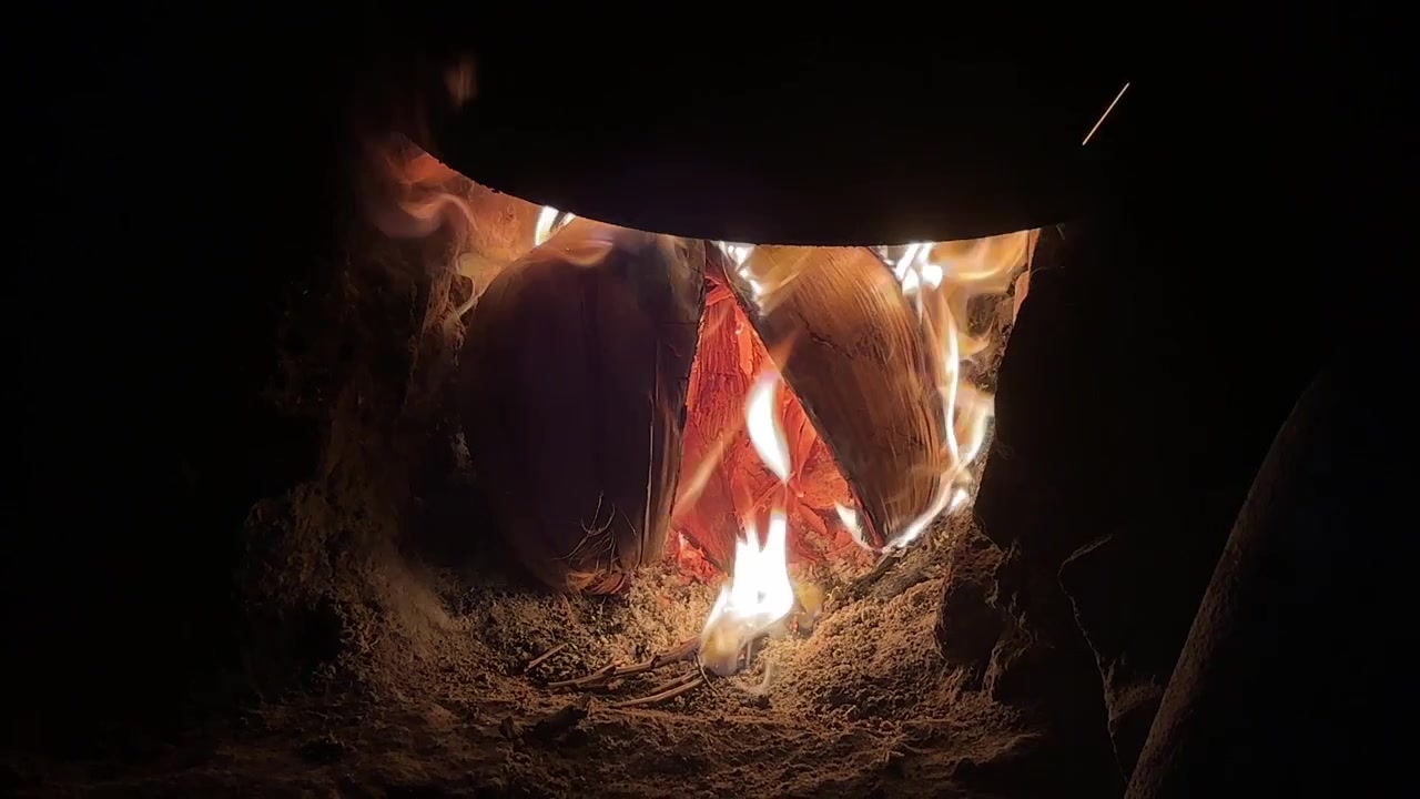 Flammer som rister kokosnøttskall i en tradisjonell jordovn
