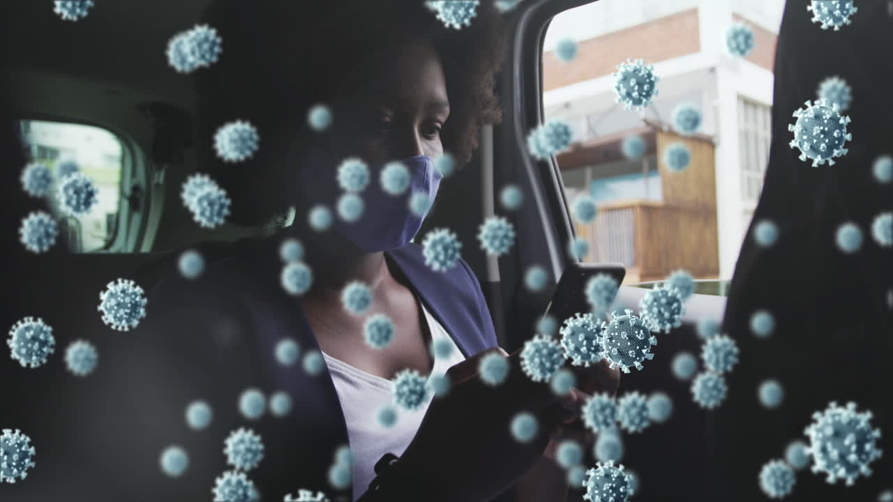 animación de células de coronavirus sobre una mujer afroamericana con máscara facial usando un teléfono inteligente en el coche