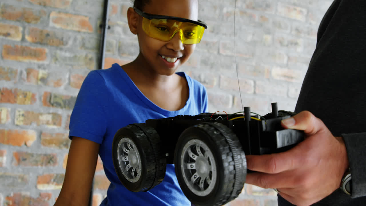 아버지 가 딸 에게 전기 모델 자동차 4k 에 대해 설명 하고 있다