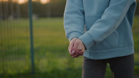 close-up of volleyball player with well-polished nails preparing to play volleyball, background features a lush open field and sports environment, showcasing athleticism and sports training