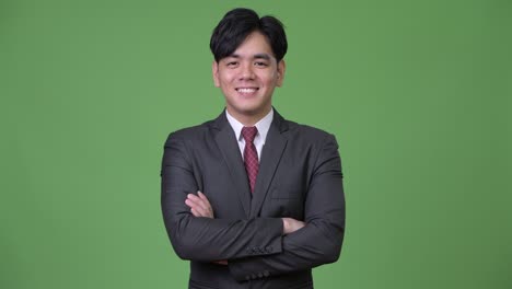 young handsome asian businessman smiling with arms crossed