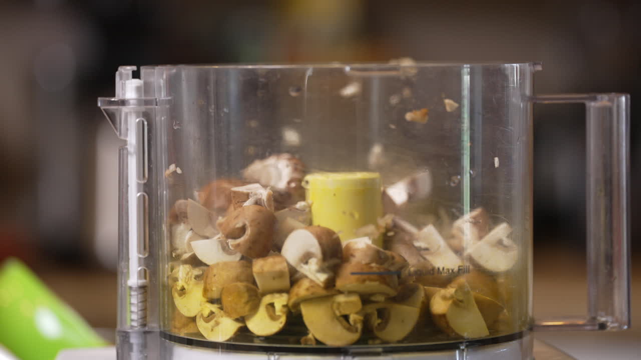 Tossing chopped mushrooms in the food processor to be ground, mixed or blended for a homemade recipe - slow motion