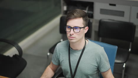 focused young professional working with multiple monitors in modern office setting. individual wearing glasses, staring at screen analyzing technical data or information