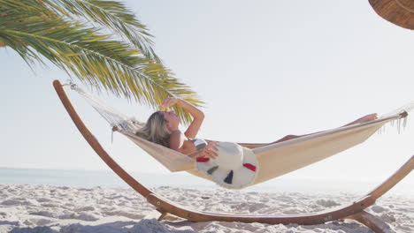 caucasian woman lying on a hammock on the beach