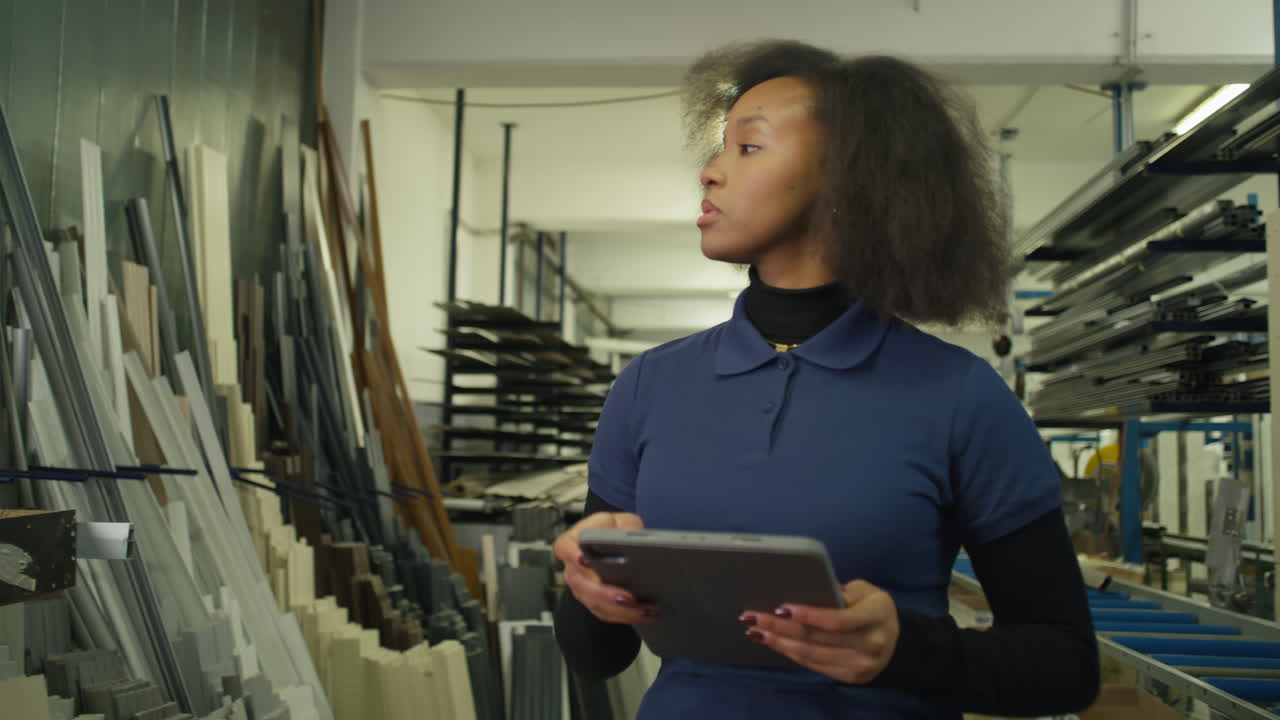 Female african american manager taking inventory in a metal factory using a tablet for modern